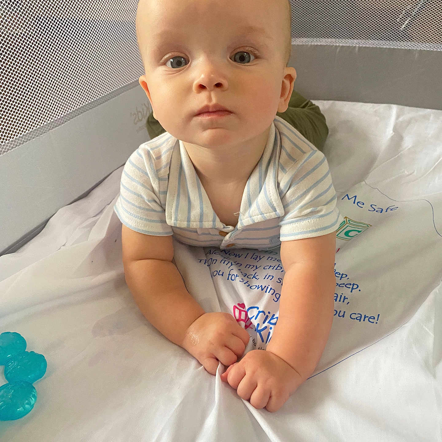 Richie joined the competition — help win amazing prizes! baby, child, infant, crib, nursery, portrait, sitting, wide_eyed, face, hands, striped_clothing, onesie, white_bedding, mesh, crib_sheet, toy, indoor, adorable, looking_at_camera, soft_lighting