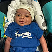 Dakota is registered to the contest to win money with this photo: baby, infant, smiling, beanie, onesie, car_seat, headrest, blue_clothing, baby_face, chubby_cheeks, portrait, cushion, seat_padding, happy, cute, young_child, hands, skin, text_on_clothing, patterned_fabric