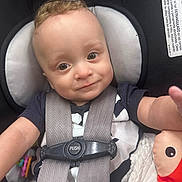 Xander is registered to the contest to win money with this photo: baby, child, car_seat, chicco, safety_harness, smile, curly_hair, toy, plush_toy, infant, closeup, person, cute, seat_belt, young_child, indoor, happy, face, clothing, portrait