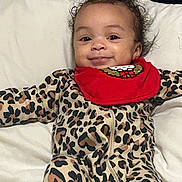 Cyonni joined the competition — help win amazing prizes! baby, infant, smile, curly_hair, leopard_print, onesie, red_bib, pillow, bed, lying_down, cute, happy, child, face, indoors, young_child, clothing, holiday, festive, portrait