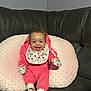Cyonni is registered to the contest to win money with this photo: baby, smiling, pink_clothing, mittens, socks, bib, hello_kitty, pillow, couch, leather, infant, happy, indoor, person, cute, seated, portrait, child, cozy, soft