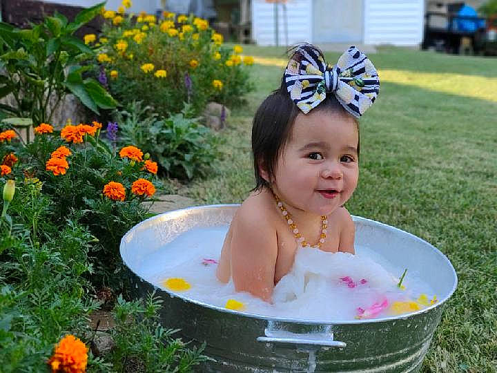 Danielle is registered to the contest to win money with this photo: baby_toddler_clothing, botany, event, flower, fun, grass, happy, headpiece, jewellery, lawn, leisure, people_in_nature, person, petal, photograph, plant, recreation, smile, summer, toddler