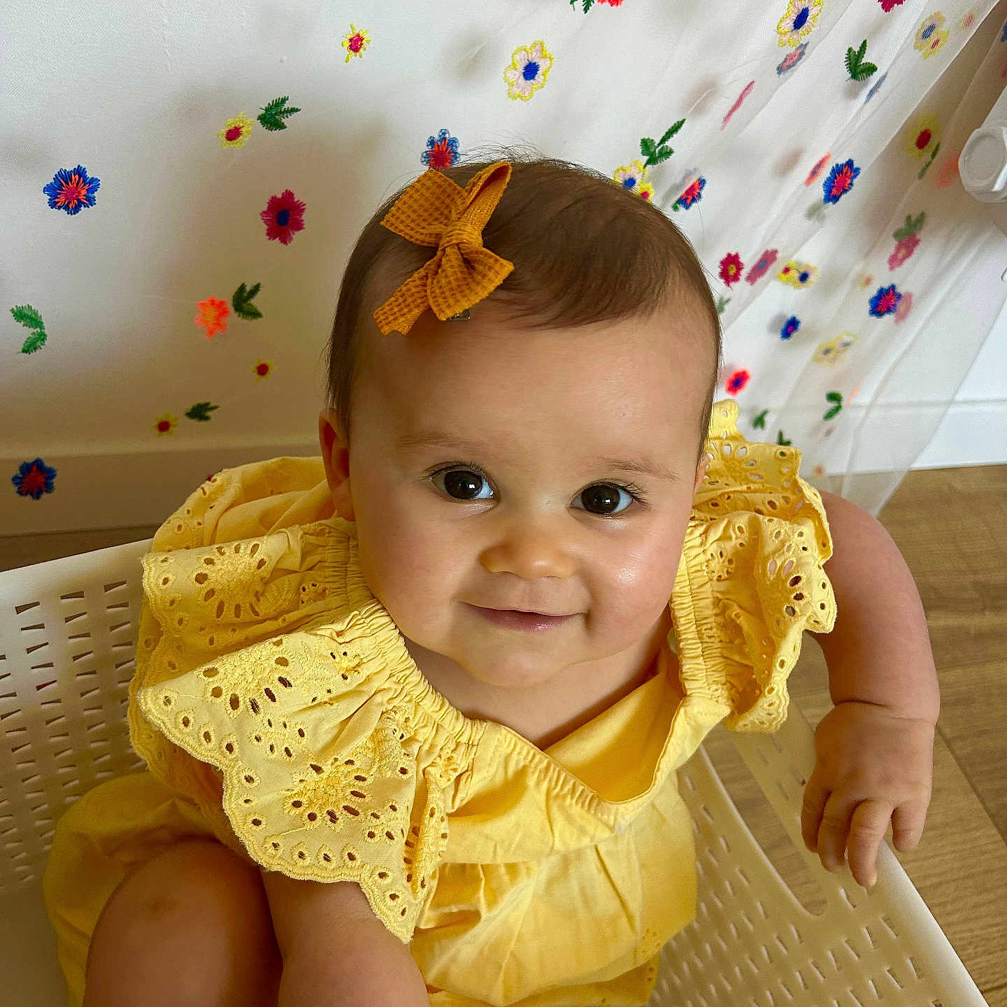 Mia participe au concours pour gagner de l'argent avec cette photo : arm, baby, basket, bow, child, curtain, cute, embroidered_flowers, face, flower_pattern, hair_accessory, happy, indoor, leg, person, portrait, smiling, toddler, wooden_floor, yellow_dress