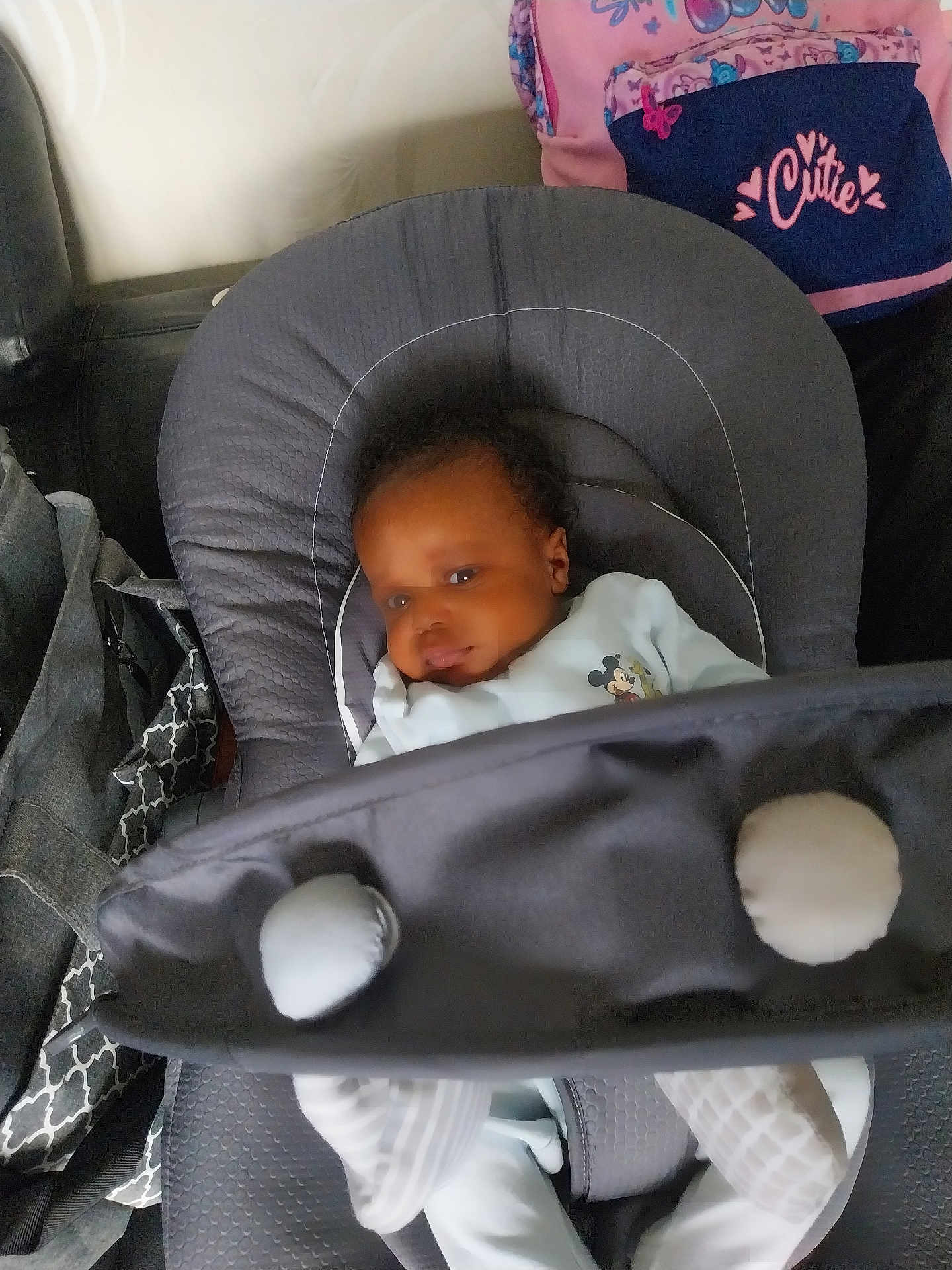 Keylann participe au concours pour gagner de l'argent avec cette photo : baby, infant, baby_seat, mickey_mouse, clothing, face, person, backpack, pink, gray, cushion, seat, indoor, soft_lighting, calm, child, home, bag, toddler, cute