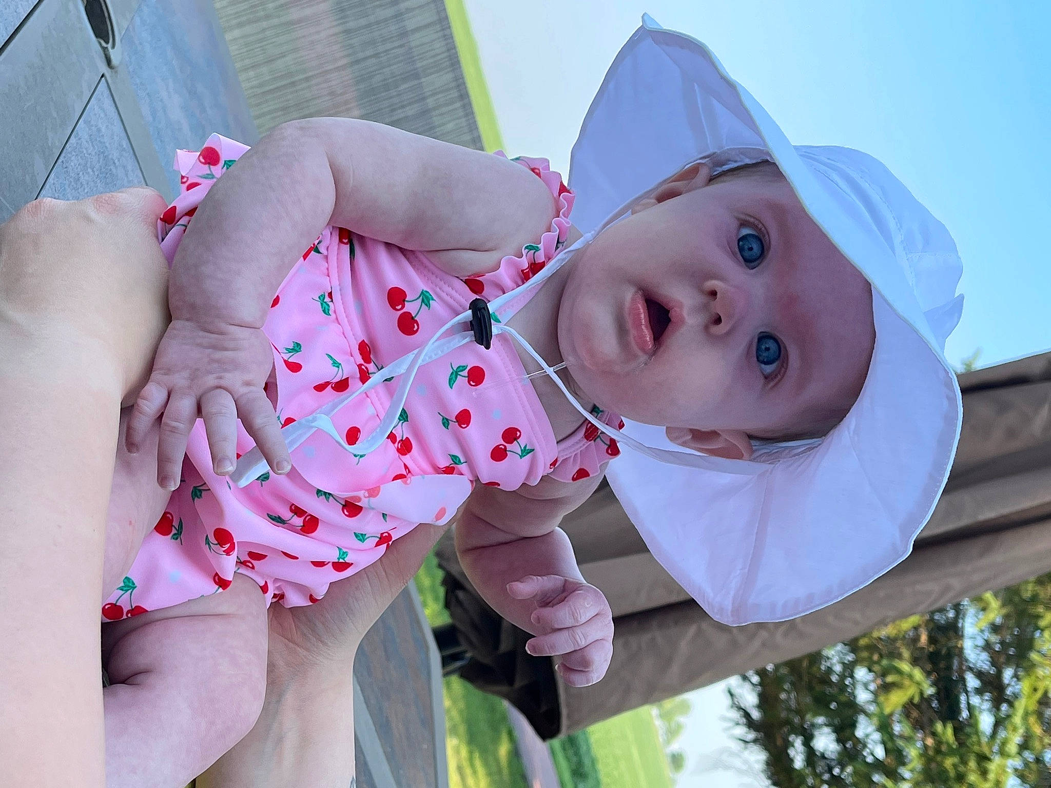Berkley is registered to the contest to win money with this photo: baby, baby_toddler_clothing, cap, facial_expression, grass, hand, happy, hat, headwear, human, human_body, lip, mouth, person, pink, plant, product, skin, sun_hat, surprise