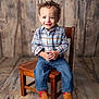 Zaylin is registered to the contest to win money with this photo: toddler, child, smiling, curly_hair, plaid_shirt, blue_jeans, cowboy_boots, wooden_chair, wooden_floor, wooden_wall, portrait, indoor, sitting, happy, cute, casual_clothing, small_chair, flooring, background, person