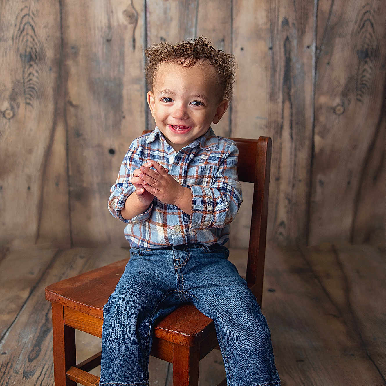 Zaylin joined the competition — help win amazing prizes! casual_clothing, child, clapping, curly_hair, cute, happy, indoor, jeans, person, plaid_shirt, portrait, rustic, sitting, smiling, studio, toddler, wooden_background, wooden_chair, wooden_floor, young_child