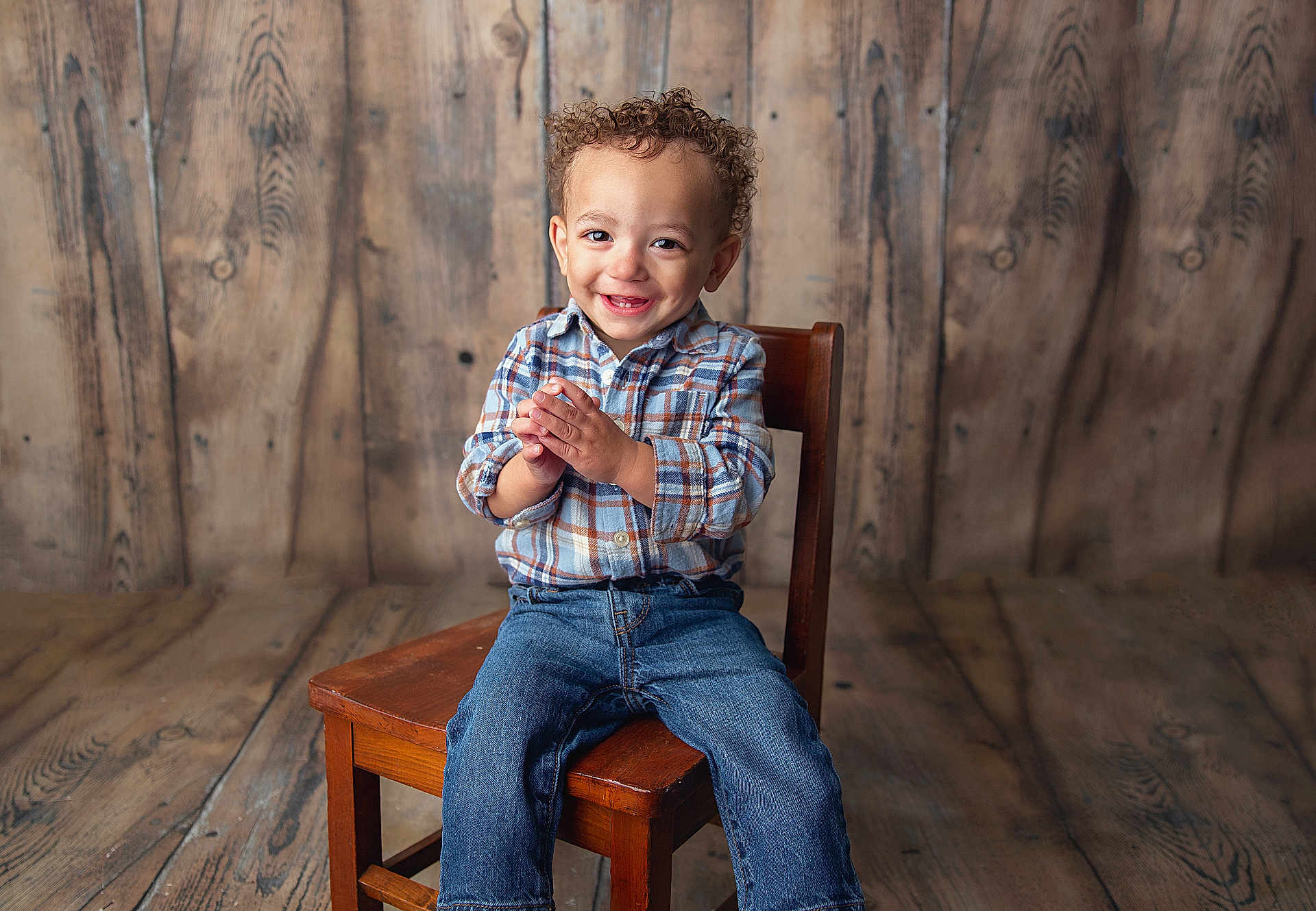 Zaylin joined the competition — help win amazing prizes! child, toddler, smiling, curly_hair, plaid_shirt, jeans, wooden_chair, wooden_floor, wooden_background, happy, clapping, casual_clothing, indoor, portrait, person, cute, young_child, sitting, studio, rustic
