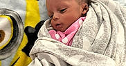 Sanai is registered to the contest to win money with this photo: baby, blanket, cartoon, child, cozy, cute, face, head, indoor, infant, lying_down, minion, newborn, pink_clothing, polka_dot, resting, soft_texture, swaddled, warm, wrapped