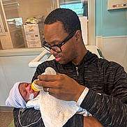 Sanai joined the competition — help win amazing prizes! adult, baby, bottle, feeding, hospital, indoor, man, newborn, person, portrait, towel, hat, glasses, love, care, family, medical, parent, holding, healthcare