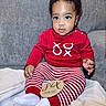 Dekhari is registered to the contest to win money with this photo: baby, child, infant, six_months, sitting, red_sweater, striped_pants, white_socks, plaque, milestone, couch, blanket, indoors, portrait, cute, smiling, face, person, clothing, young