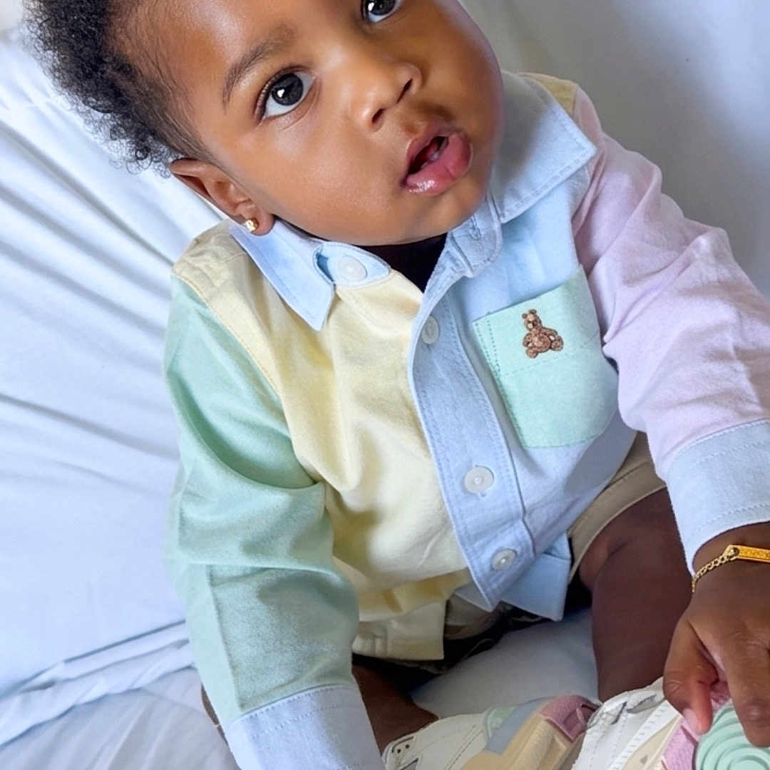 Dekhari joined the competition — help win amazing prizes! toddler, child, baby, curly_hair, pastel_clothing, sneakers, bed, white_bed, portrait, cute, curious, earrings, bracelet, indoor, person, fashion, footwear, hand, sitting, young_child