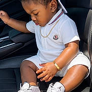 Dekhari is registered to the contest to win money with this photo: toddler, child, white_outfit, cap, sneakers, car_seat, gold_bracelet, gold_chain, black_hair, side_profile, cute, indoors, leather_seat, fashion, footwear, casual, portrait, young_child, sitting, daylight