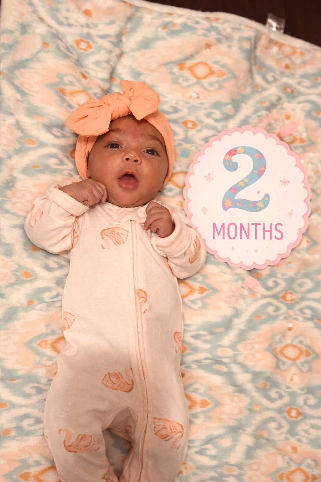 Kaylani joined the competition — help win amazing prizes! baby, infant, headband, bow, milestone_card, two_months, blanket, onesie, lying_down, portrait, face, eyes_open, mouth_open, pastel, pattern, pink, hands, cute, newborn, soft_texture