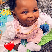 Jycee is registered to the contest to win money with this photo: baby, child, smiling, curly_hair, pink_overalls, white_socks, play_mat, colorful, indoor, carpet, toy, happy, cute, portrait, sitting, infant, person, face, young_child, cozy