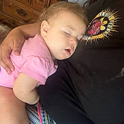 Jazmine is registered to the contest to win money with this photo: baby, sleeping, child, pink_shirt, arm, person, patterned_fabric, colorful, resting, indoor, furniture, wooden_drawer, comfort, cuddle, hand, face, peaceful, casual_clothing, closeup, relaxation