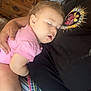 baby, sleeping, child, pink_shirt, arm, person, patterned_fabric, colorful, resting, indoor, furniture, wooden_drawer, comfort, cuddle, hand, face, peaceful, casual_clothing, closeup, relaxation