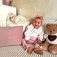 Louisa a rejoint le concours — aidez-le/la à gagner de superbes lots ! baby, child, pink, headband, smile, plush_toy, teddy_bear, pillow, embroidery, white_blouse, cozy, bed, soft_texture, cute, happy, indoor, portrait, person, sitting, clothing