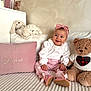 baby, child, pink, headband, smile, plush_toy, teddy_bear, pillow, embroidery, white_blouse, cozy, bed, soft_texture, cute, happy, indoor, portrait, person, sitting, clothing