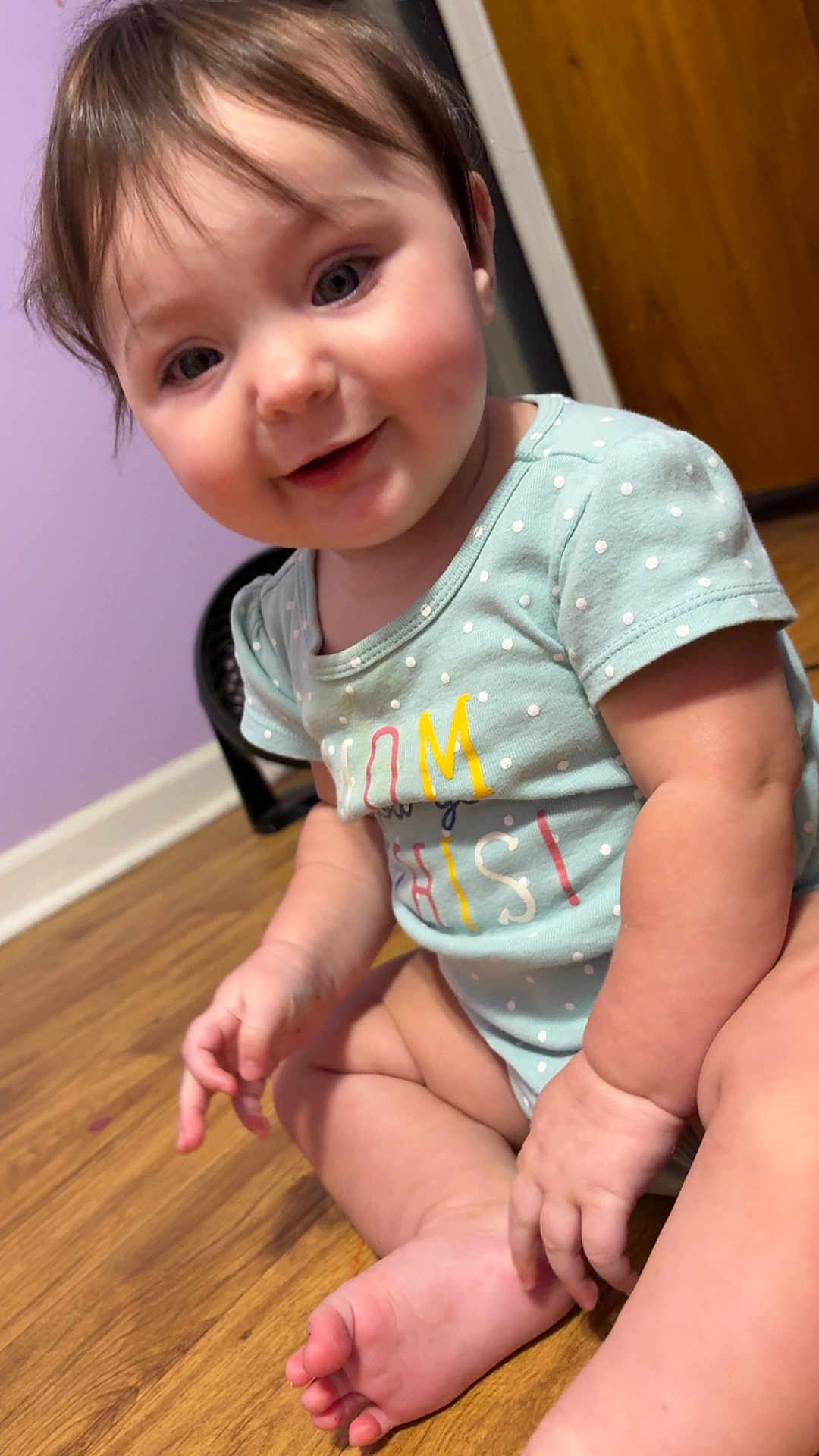 Addilyn joined the competition — help win amazing prizes! baby, child, infant, smiling, sitting, onesie, polka_dot, floor, wooden_floor, indoor, face, hand, foot, cute, happy, young_child, purple_wall, door, skin, person