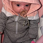 Nelyah participe au concours pour gagner de l'argent avec cette photo : baby, pacifier, hoodie, pink, grey_clothing, infant, child, seat, toy, soft_toy, cute, indoor, portrait, face, small_hand, zipped_jacket, baby_accessory, expression, closeup, sitting