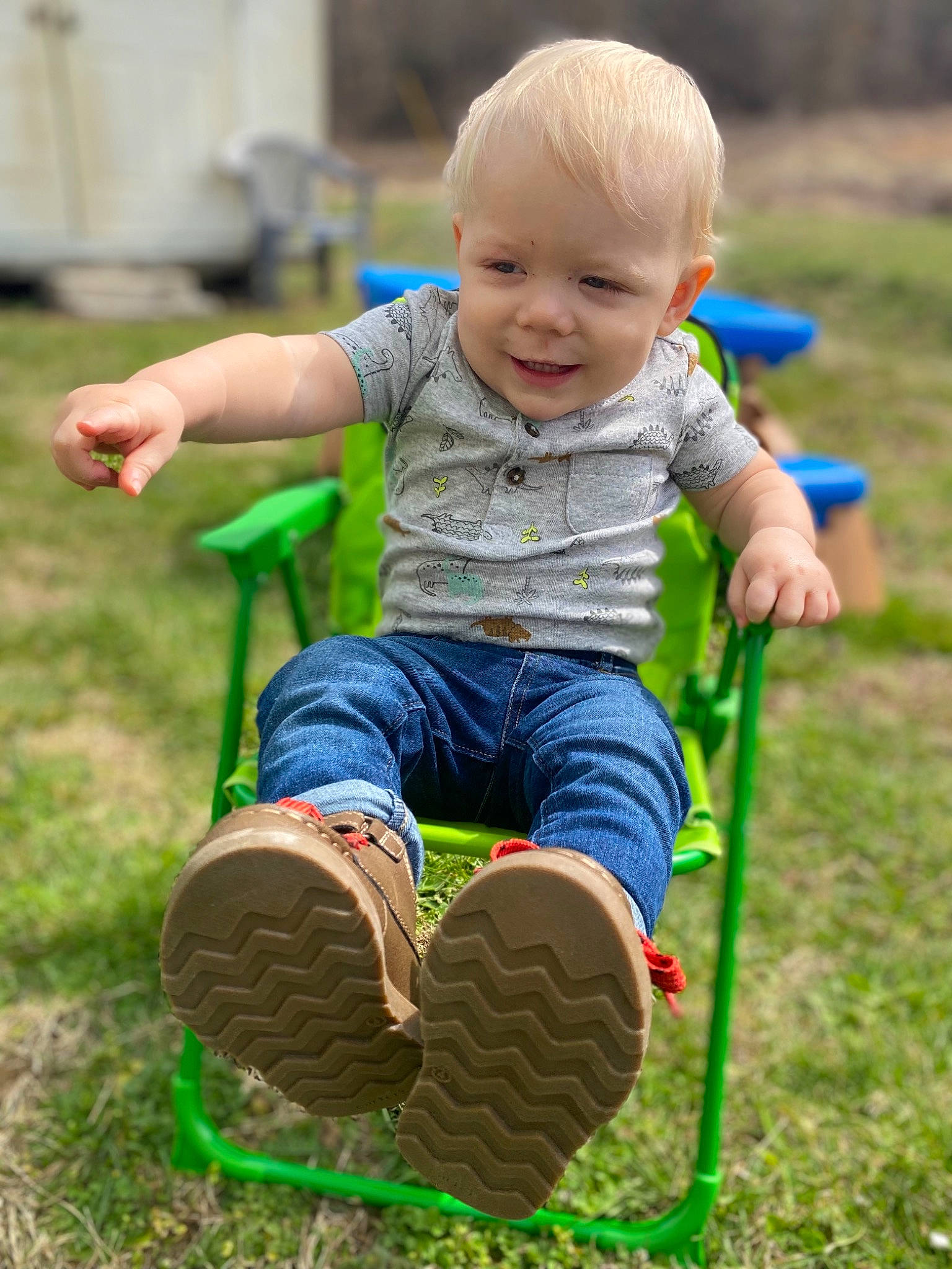 Bentlee is registered to the contest to win money with this photo: baby_toddler_clothing, chair, child, face, fun, grass, happy, lawn, leisure, nature, people_in_nature, person, public_space, recreation, sitting, smile, snapshot, summer, t_shirt, toddler