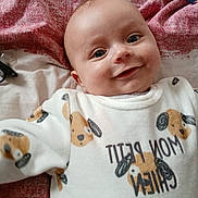 Enzo a rejoint le concours — aidez-le/la à gagner de superbes lots ! baby, bed, blanket, child, cozy, cute, dog_pattern, fabric, face, happy, indoors, infant, onesie, person, portrait, sleepwear, smiling, text_on_clothing, toddler, young_child