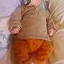 Enzo participe au concours pour gagner de l'argent avec cette photo : baby, infant, bed, pillow, clothing, socks, pacifier, sleepwear, blanket, person, child, indoor, soft_focus, orange_pants, brown_sweater, lying_down, headboard, cute, cozy, resting
