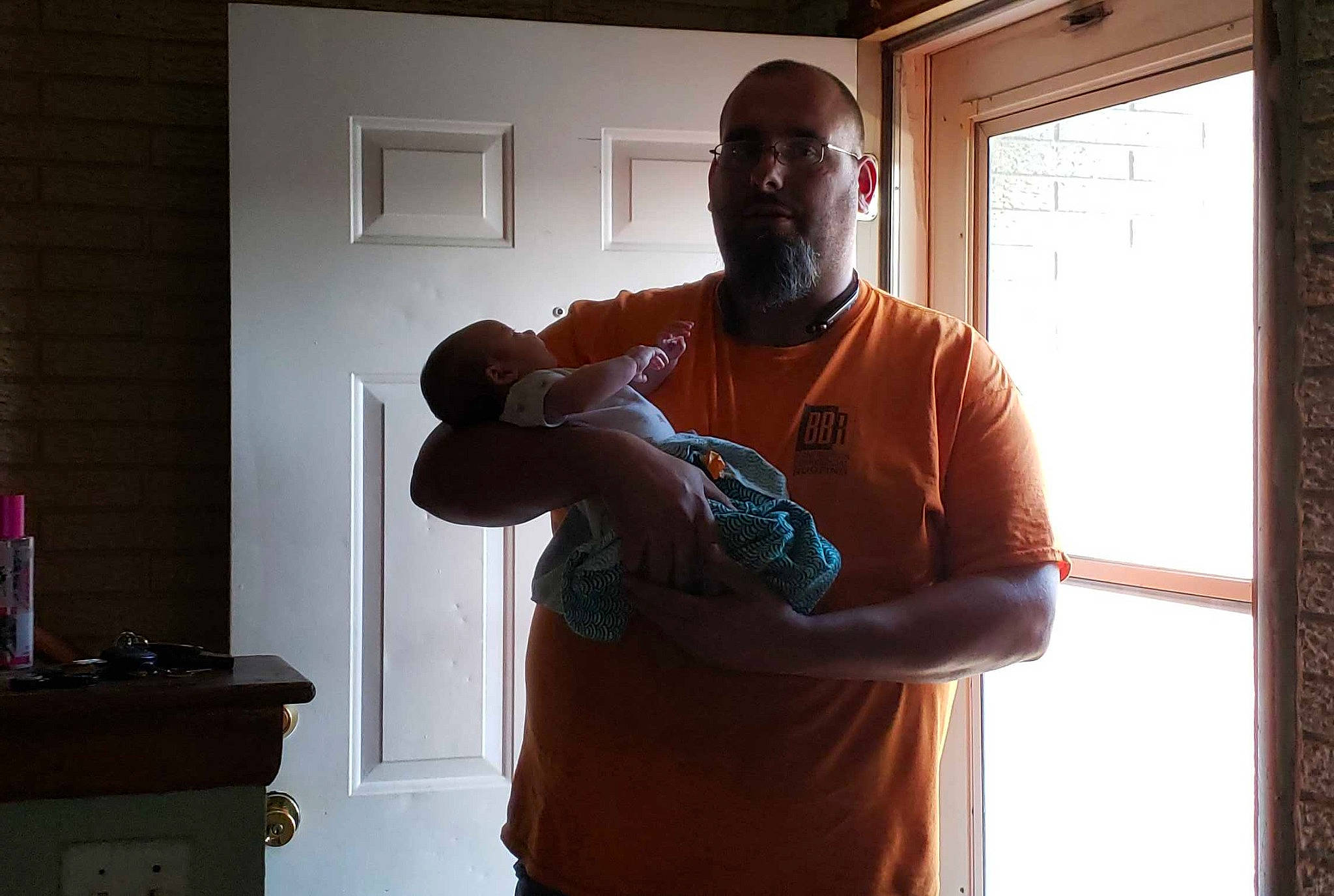 Xane is registered to the contest to win money with this photo: arm, facial_hair, finger, hand, hardwood, house, joint, muscle, person, room, shoulder, standing, t_shirt, vacation, window