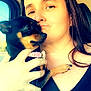 animal, black_top, calm, car, casual, close_up, collar, cute, dog, face, hand, holding, indoor, pet, portrait, relaxed, seatbelt, small_dog, tan_markings, woman