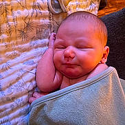 Ronin is registered to the contest to win money with this photo: baby, sleeping, blanket, pacifier, infant, wrapped, cozy, peaceful, soft, face, closeup, child, newborn, resting, indoors, fabric, pattern, cute, warm_light, relaxing