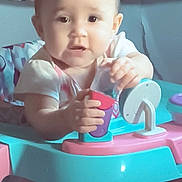 Nevaeh joined the competition — help win amazing prizes! baby, child, infant, sitting, toy, play_center, colorful, indoors, portrait, face, eyes, hands, curious, casual, home, cushion, patterned_background, plastic, social_media_screenshot, sunday_text