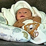 Carter is registered to the contest to win money with this photo: baby, infant, child, portrait, face, wide_eyed, sitting, lying_down, blanket, swaddle, couch, cushion, lion, stuffed_animal, animal_print, clothing, brown, white, indoor, cozy
