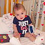 Keniel joined the competition — help win amazing prizes! baby, infant, hospital, crib, medical_equipment, nasal_cannula, onesie, blue_clothing, white_booties, toy, heart_overlay, striped_blanket, child, sitting, cute, smiling, medical_band, indoor, healthcare, person