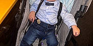 Keniel is registered to the contest to win money with this photo: baby, child, stroller, medical_tubes, nasal_cannula, blue_blanket, bow_tie, suspenders, denim_pants, shoes, smiling, indoor, person, infant, cute, healthcare, happy, seated, clothing, footwear