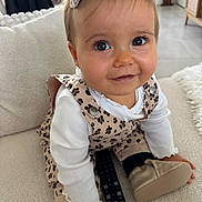 Julia a rejoint le concours — aidez-le/la à gagner de superbes lots ! baby, child, face, smile, couch, remote_control, clothing, hair_bow, indoor, person, happy, sitting, white_shirt, leopard_print, footwear, hand, eyes, cute, cozy, home