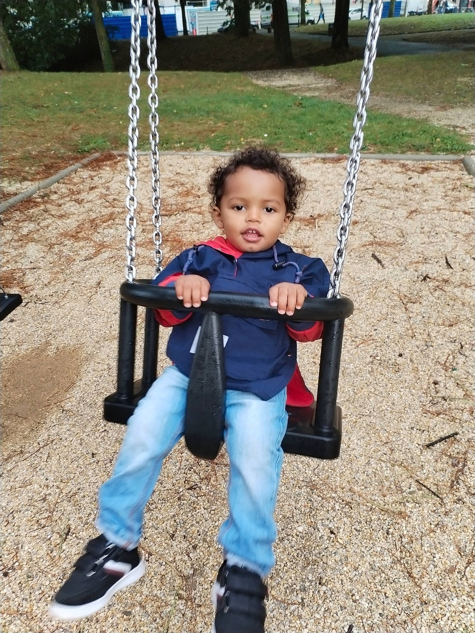 Giannis a rejoint le concours — aidez-le/la à gagner de superbes lots ! baby, baby_toddler_clothing, child, city, electric_blue, fun, grass, happy, leisure, outdoor_play_equipment, person, plant, play, playground, recreation, sitting, swing, toddler, tree, white