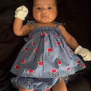 Kehlani is registered to the contest to win money with this photo: baby, infant, child, portrait, lying_down, smiling, wide_eyed, floral_dress, blue_clothing, white_mittens, hair_bows, flowers, dark_blanket, indoor, closeup, full_body, fashion, cute, photography, face