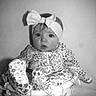 Brynlee is registered to the contest to win money with this photo: baby, child, basket, headband, bow, floral_pattern, clothing, portrait, black_and_white, wicker, cute, infant, sitting, expression, curious, indoors, soft_lighting, fabric, texture, decorative