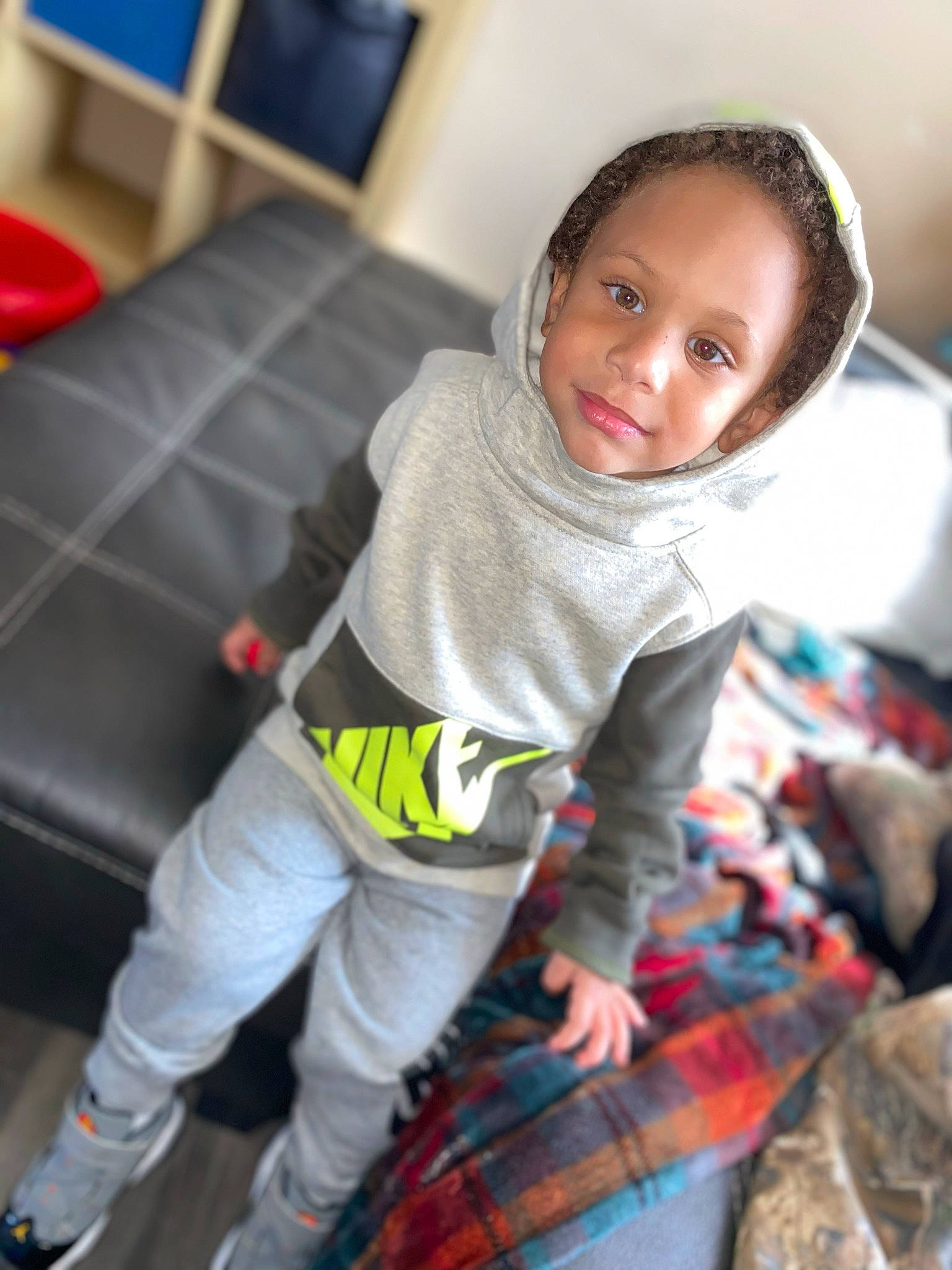 Rashawn is registered to the contest to win money with this photo: baby_toddler_clothing, child, couch, facial_expression, flash_photography, flooring, fun, happy, human_leg, joy, leg, pajamas, pattern, person, plaid, sitting, smile, sneakers, sock, t_shirt
