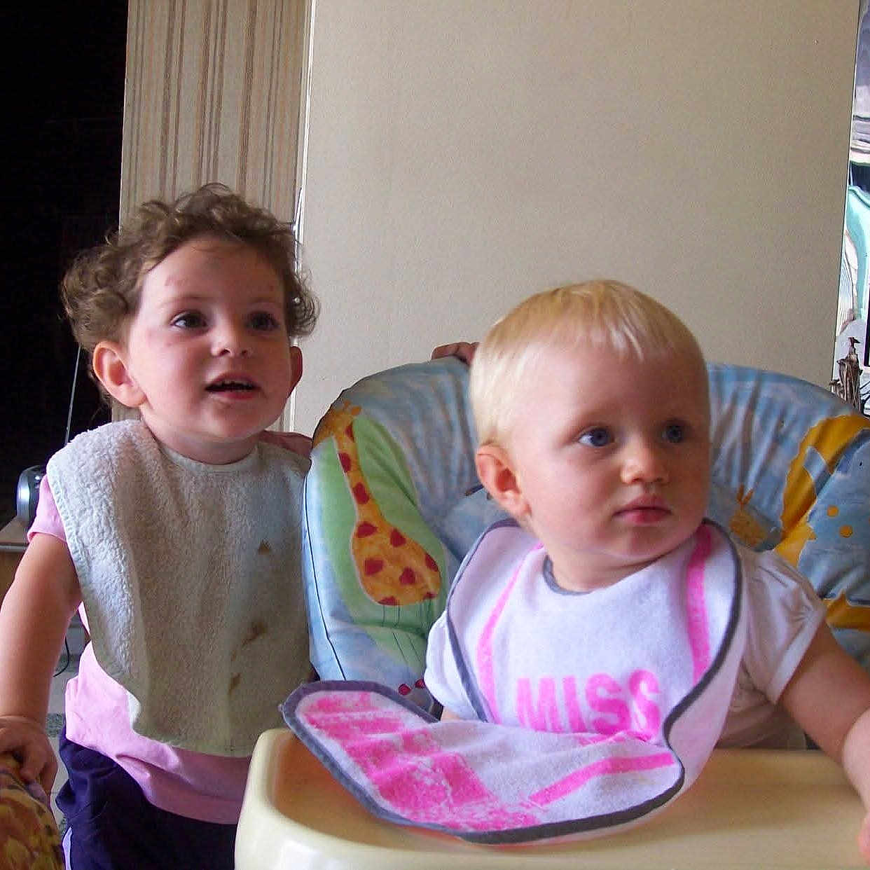 Milene a rejoint le concours — aidez-le/la à gagner de superbes lots ! baby, bib, blonde, child, clothing, curiosity, curly_hair, expression, face, floor, furniture, hand, high_chair, home, indoor, person, seat, table, television, toddler