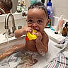 baby, bath, bathtub, bubbles, child, curly_hair, face, foam, faucet, mirror, plastic_toy, rubber_duck, sink, soap, striped_towel, water, wet_skin, young_child, bathroom, personal_care