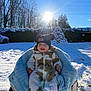 baby, child, snow, winter, sunlight, blue_sky, hat, snowsuit, blanket, outdoor, smiling, happy, chair, trees, car, sunflare, cold, nature, daylight, fuzzy_clothing