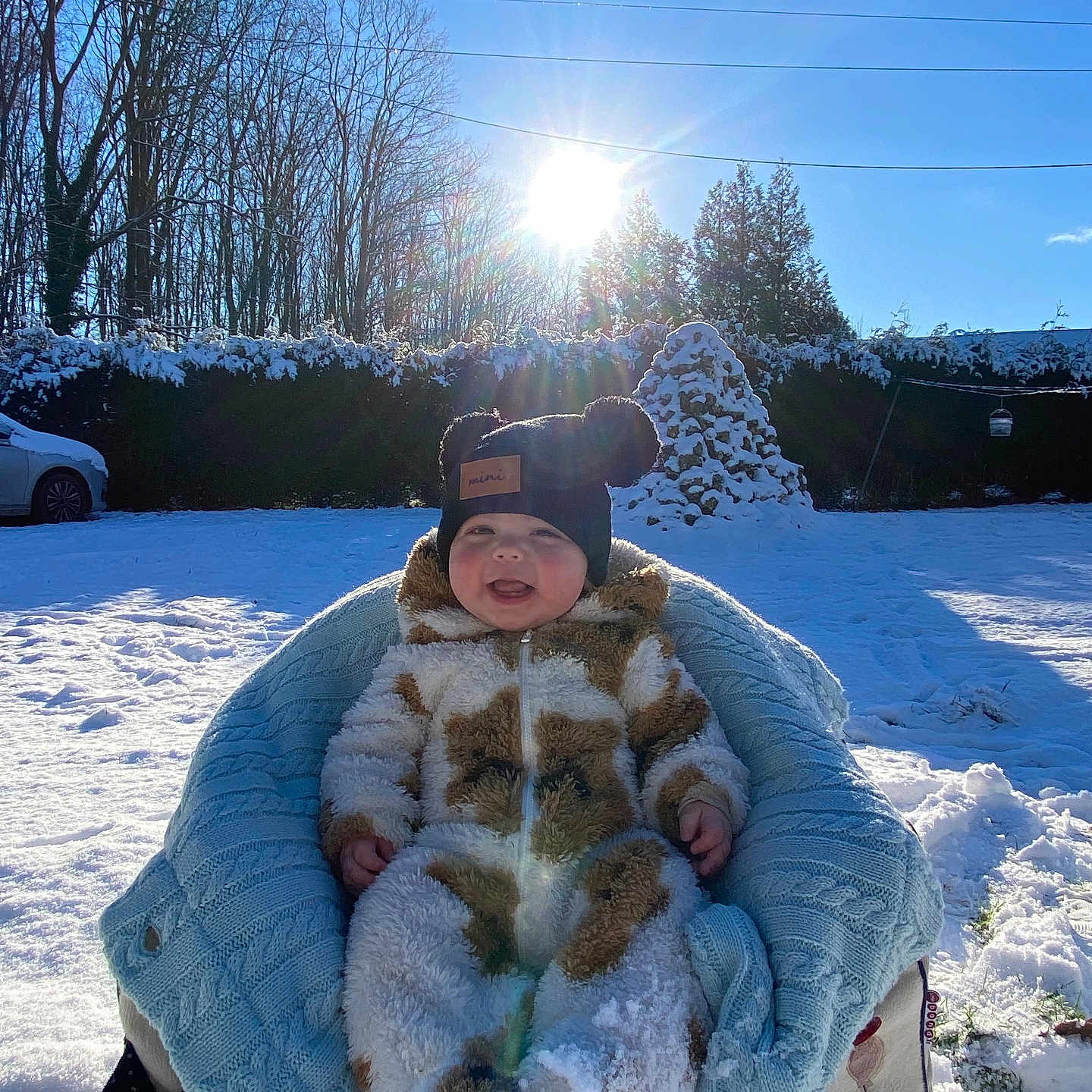 Milyo a rejoint le concours — aidez-le/la à gagner de superbes lots ! baby, blanket, blue_sky, car, chair, child, cold, daylight, fuzzy_clothing, happy, hat, nature, outdoor, smiling, snow, snowsuit, sunflare, sunlight, trees, winter