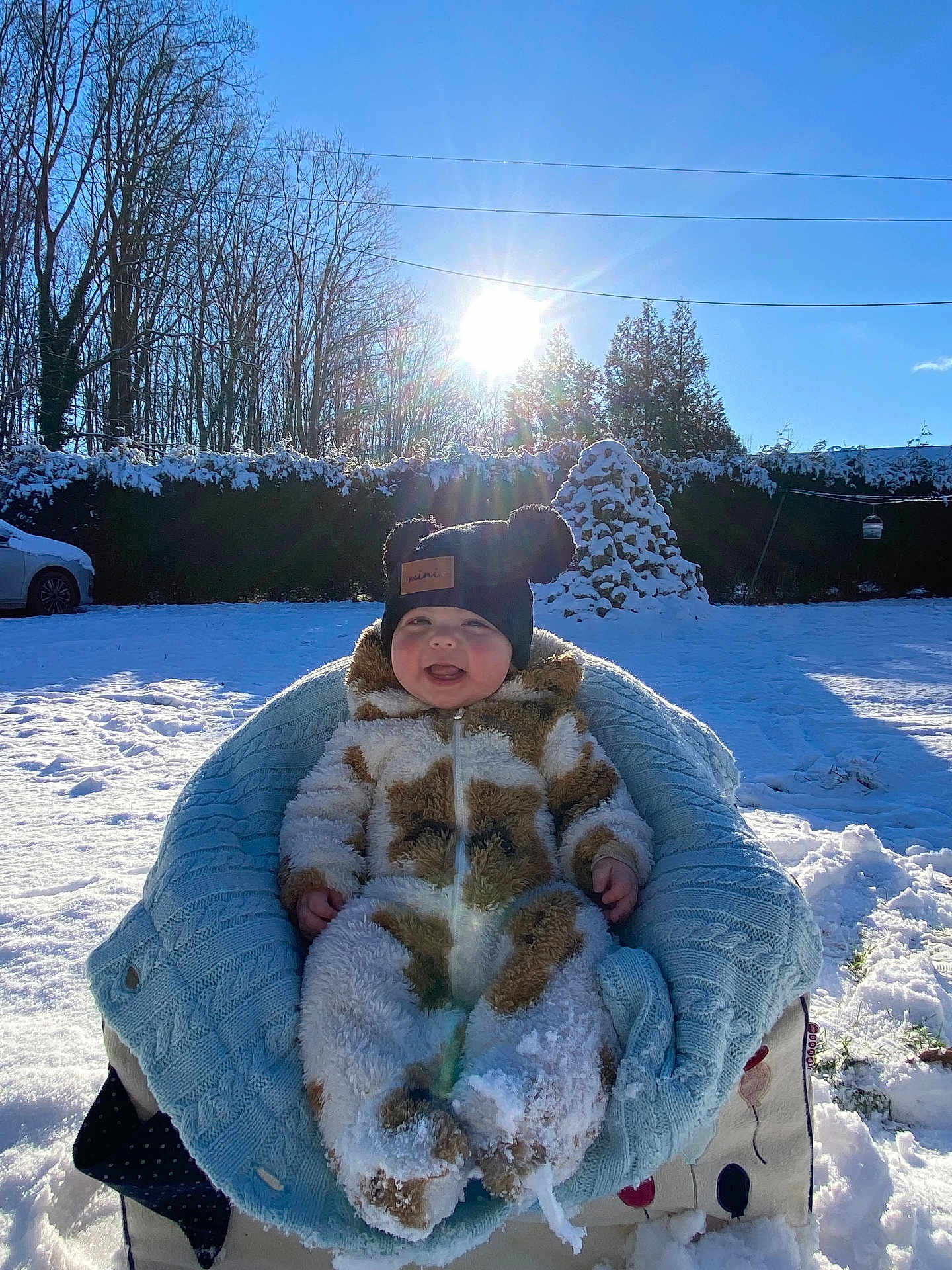 Milyo a rejoint le concours — aidez-le/la à gagner de superbes lots ! baby, child, snow, winter, sunlight, blue_sky, hat, snowsuit, blanket, outdoor, smiling, happy, chair, trees, car, sunflare, cold, nature, daylight, fuzzy_clothing