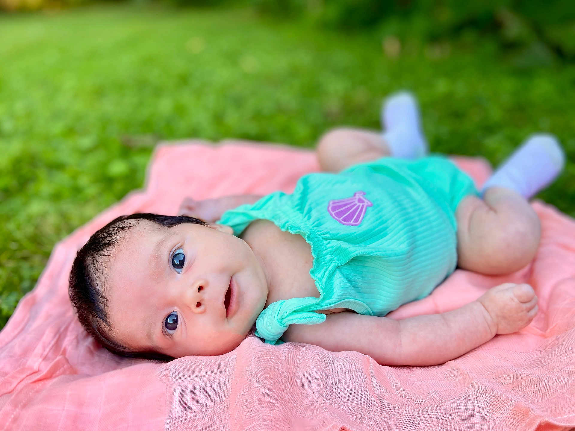 Demi joined the competition — help win amazing prizes! baby, infant, onesie, blanket, outdoor, grass, green, pink, cute, portrait, soft, newborn, child, lying_down, face, skin, head, expression, small, feet