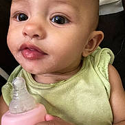 Maxine is registered to the contest to win money with this photo: baby, baby_bottle, bottle, child, close_up, eyes, face, feeding, green_clothing, hand, indoor, infant, innocent, looking_at_camera, person, photography, pink, portrait, sitting, smiling