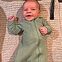 Ashton is registered to the contest to win money with this photo: baby, infant, smiling, green_onesie, carpet, hand, fist, cute, lying_down, happy, child, portrait, indoor, cozy, soft_texture, young, playful, human, person, clothing