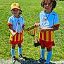 child, children, soccer, trophy, medal, sports, grass, outdoor, sunny, uniform, team, field, cap, curly_hair, shorts, socks, shoes, celebration, happy, competition