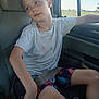 Christopher is registered to the contest to win money with this photo: arm, boy, car_seat, casual_clothing, child, daylight, face, hair, indoors, leg, looking_away, relaxed, seat, seatbelt, shorts, skin, tshirt, vehicle_interior, window, young
